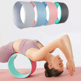 Woman using yoga wheel for back stretch on exercise mat, multi-color yoga wheels displayed above.